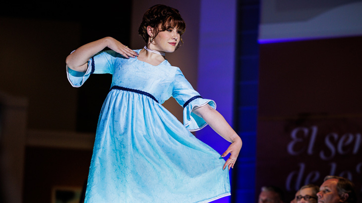 A BYU student in a light blue dress in the Museum of Art runway show